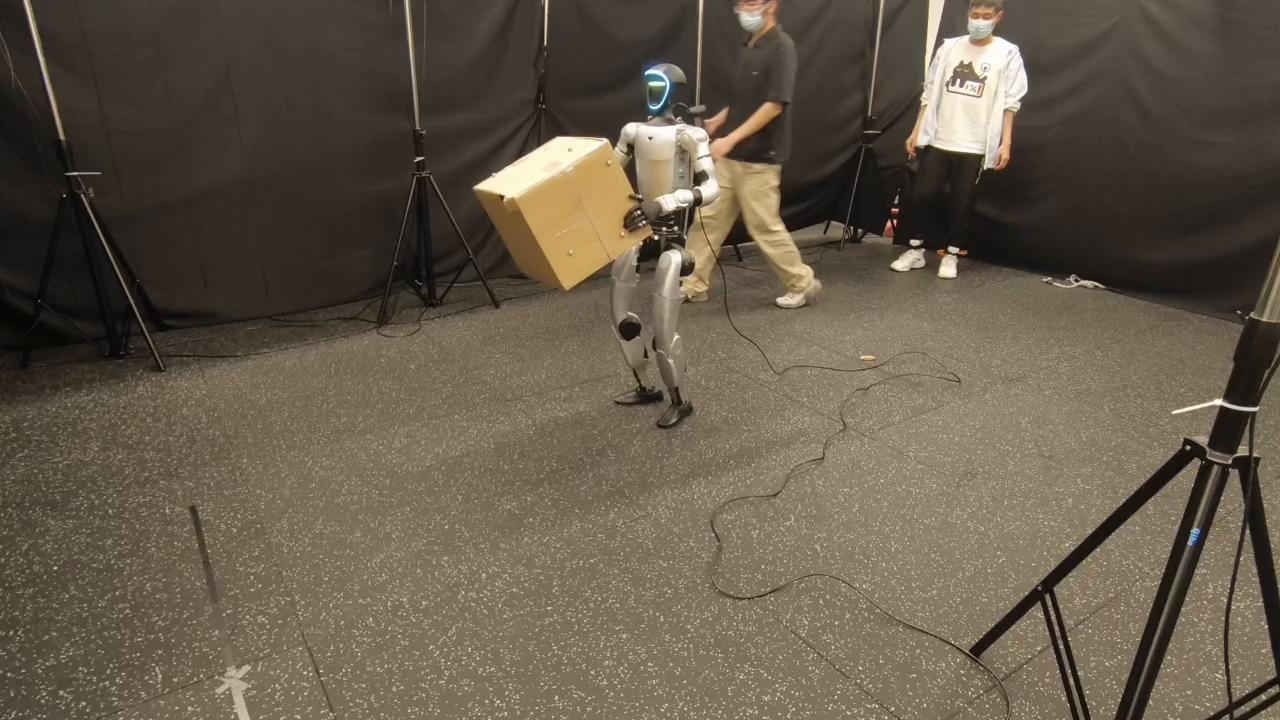 I-BFM humanoid carrying a box in the real-world robustness demonstration.